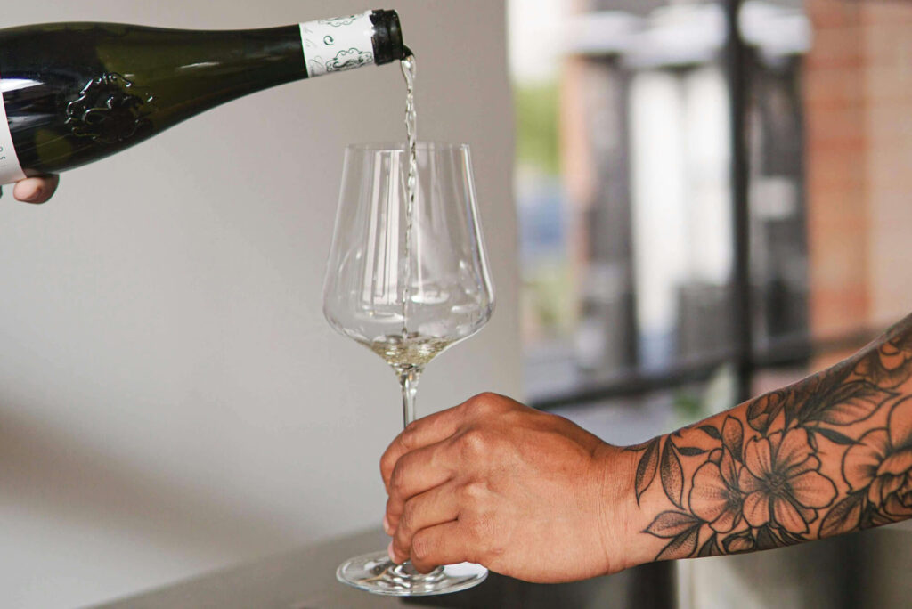 Wine being poured into a wine glass held by a hand